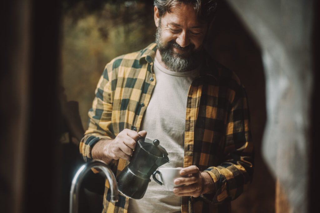 Ein reifer mann bereitet mit einem Espressokocher sehr leckeren Espressokaffee zu